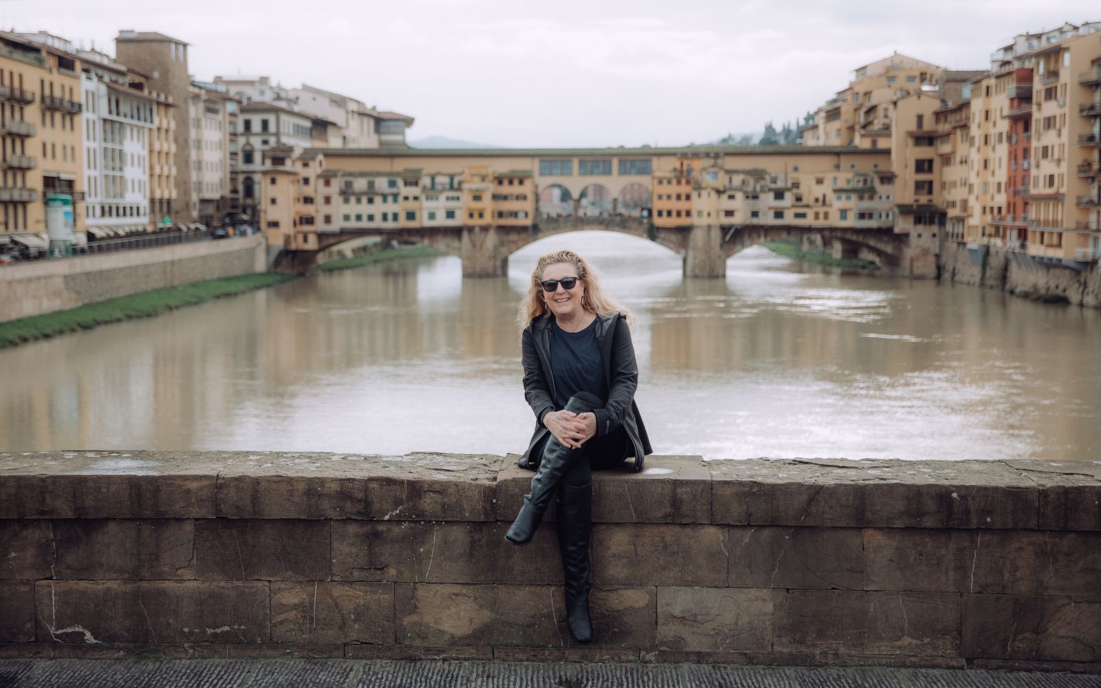 Elisabetta, Owner of My Italian Decor sits in front of the Ponte Vecchio Bridge in Florence, Italy.