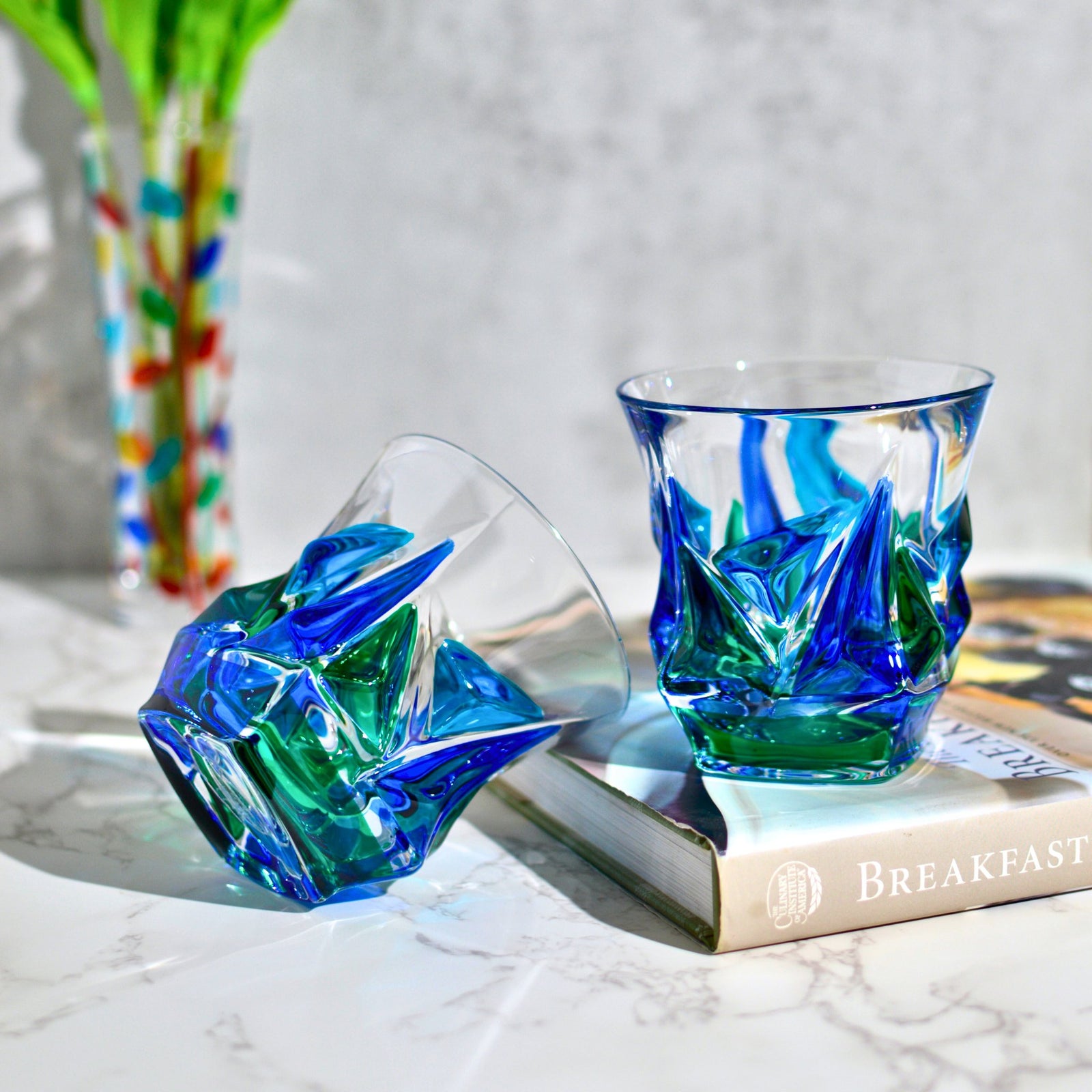 DZ Italian Crystal Empress tumblers in blue and green set of 2, front view on marble surface showcasing elegant glass design.