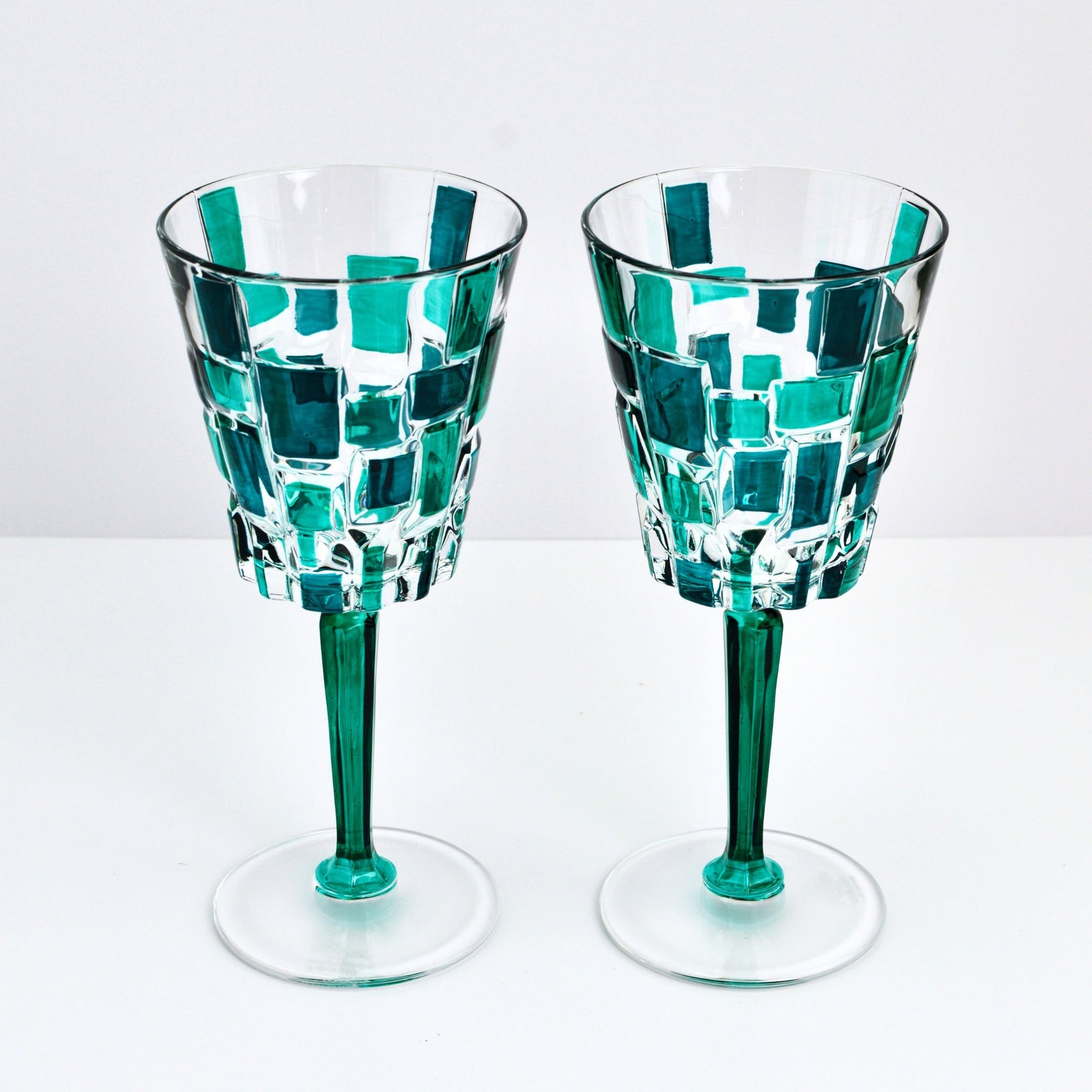 Pair of DZ Etna hand-painted Italian crystal wine glasses in emerald green, displayed lying down.