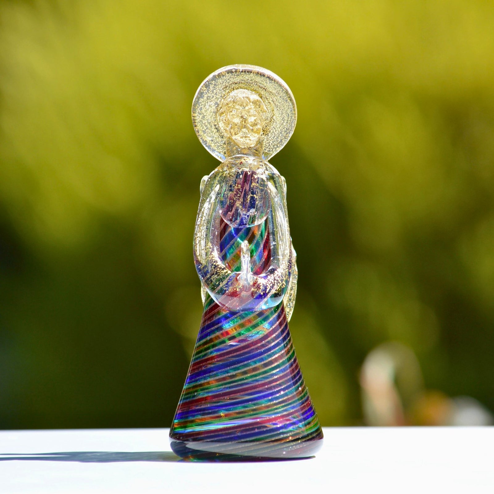 Murano Glass Filigrana Angel figurine made in Italy, showcasing intricate glass craftsmanship and vibrant colors outdoors.