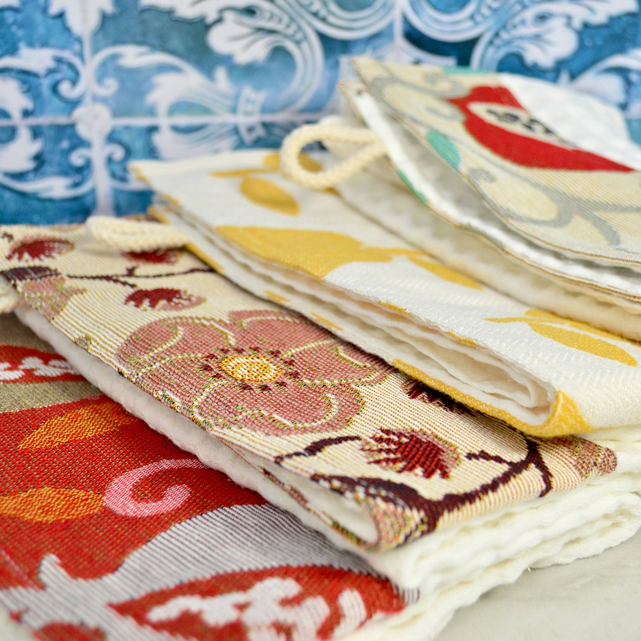 Close-up of assorted colorful kitchen towels from My Italian Decor, made in Italy, featuring elegant table linen designs.
