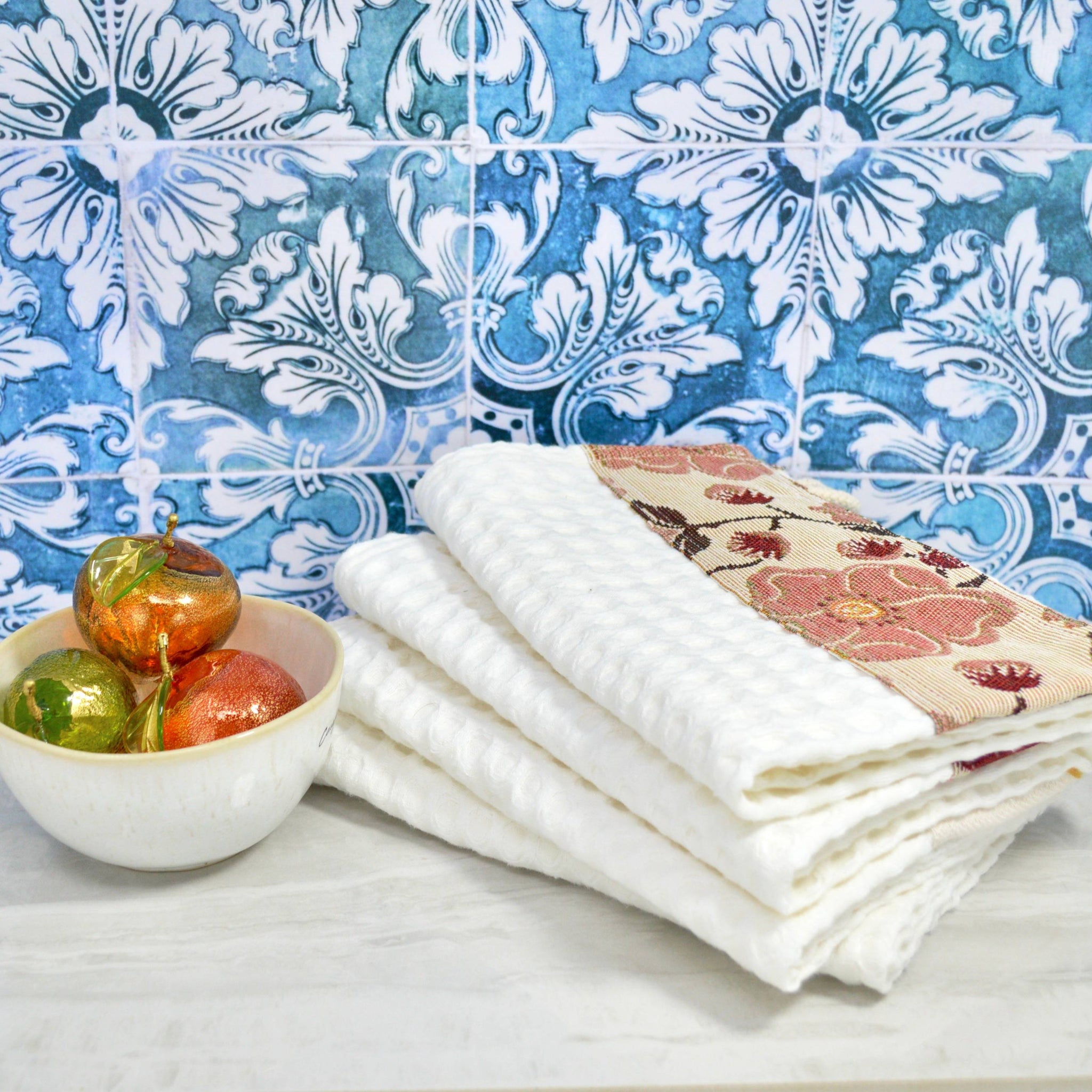 Colorful Italian kitchen towel by My Italian Decor next to a bowl of Murano glass fruit, showcasing vibrant table linens.