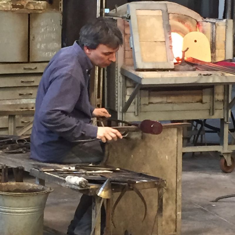 Glass artisan at furnace making glass art