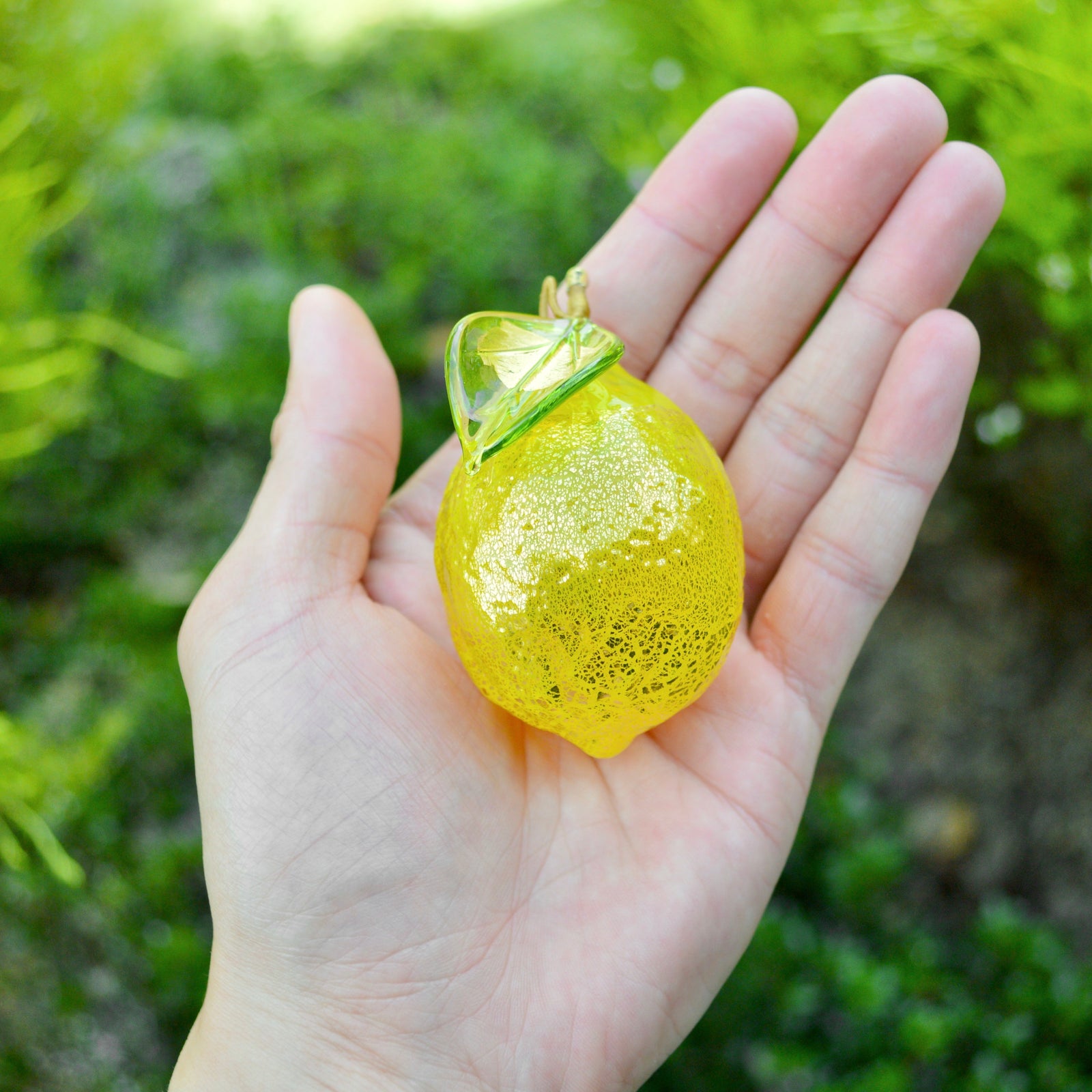 Hand-blown Murano glass lemon figurine from Italy, artificial floral decor with vibrant yellow color on white table.