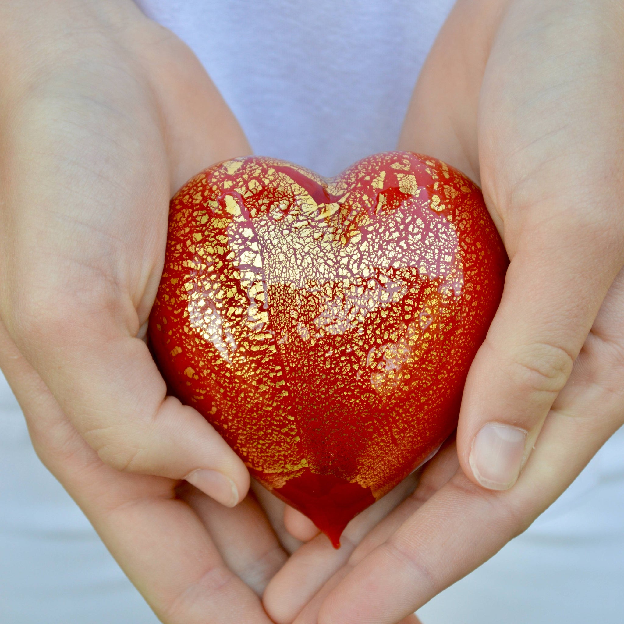 Hand holding a colorful Murano glass heart figurine with 24 karat gold accents, made in Italy by MyItalianDecor.
