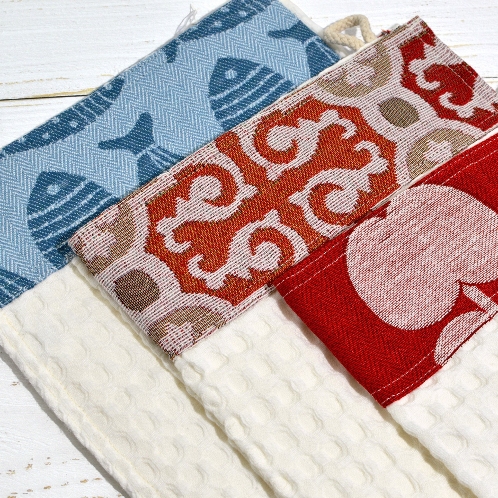 Three colorful Italian kitchen towels with different patterns, made by My Italian Decor, displayed overhead on a table.