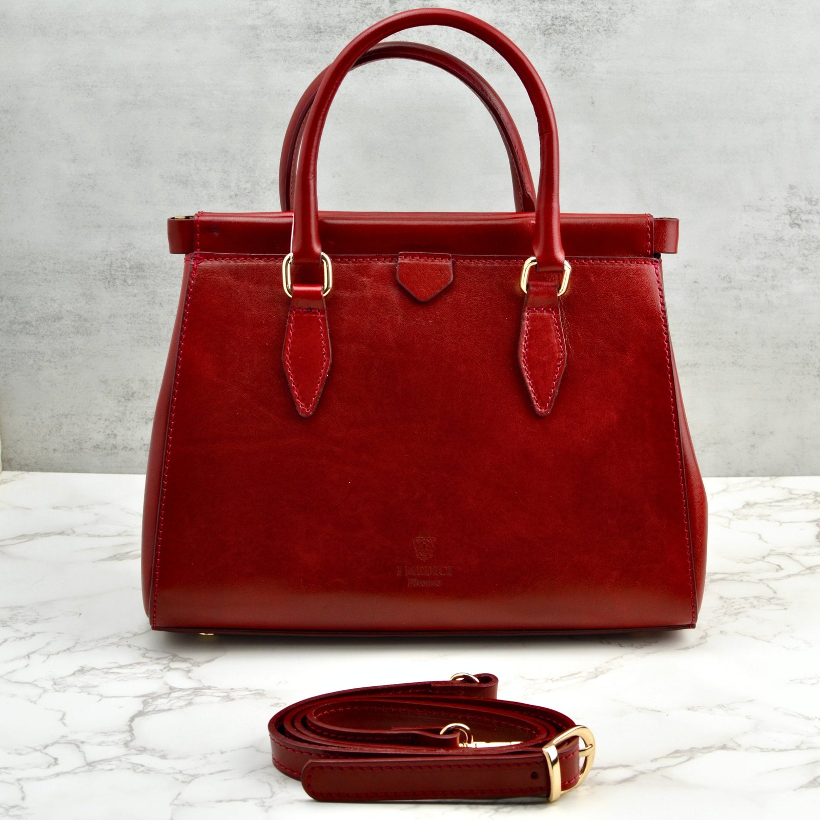 Red Lizzy & Betta Italian leather top handle handbag with structured design and gold-tone hardware, stylishly displayed.