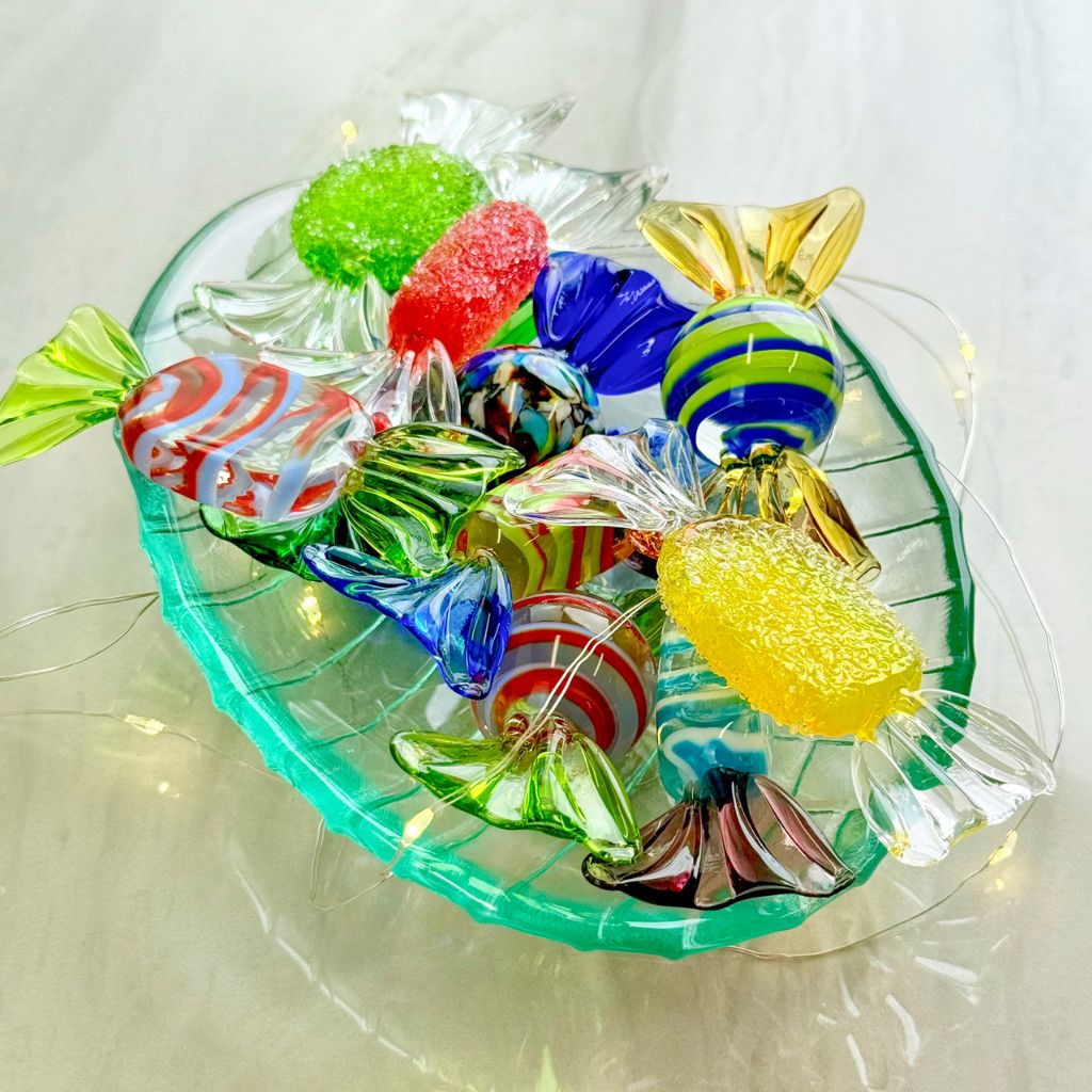 Colorful glass candy figurines on a clear glass plate with a white background