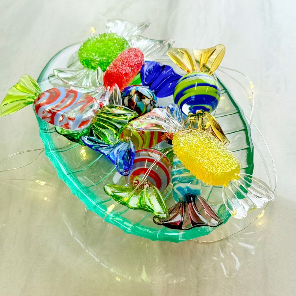 Colorful glass candy pieces on a clear stand with a white background