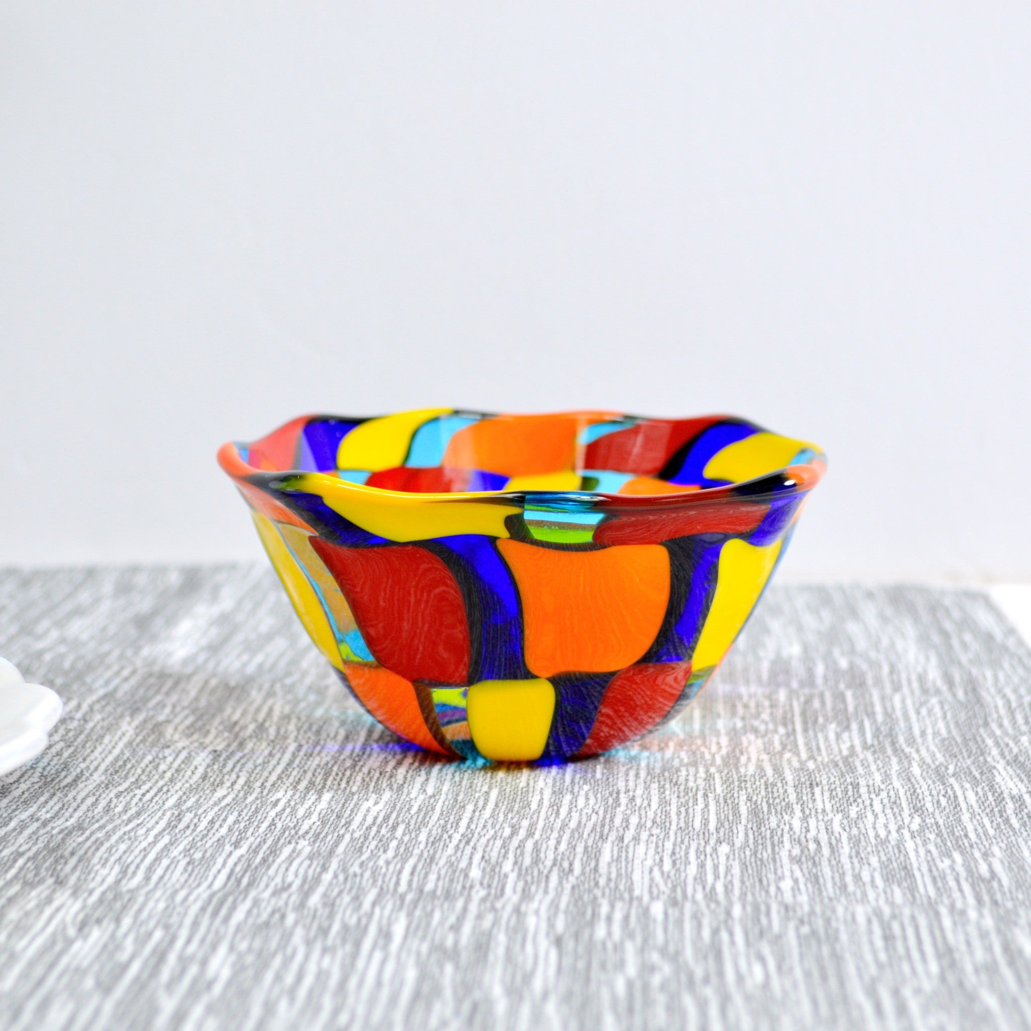 Side view of a Murano glass bowl in bright orange, red, yellow and blue.