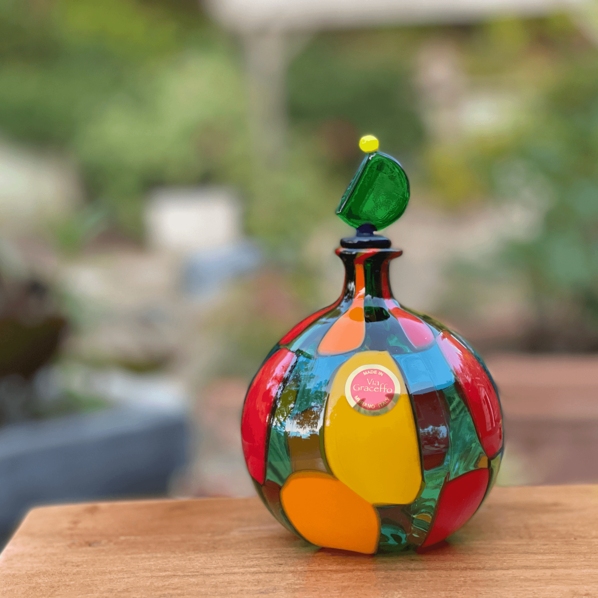 Handblown Murano glass perfume bottle with a green top, featuring intricate glass art design by Pazzia for decorative display.