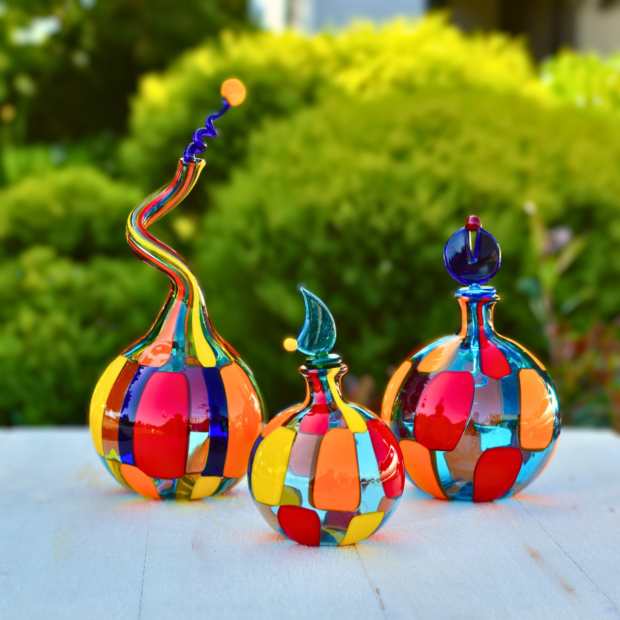 Handblown Murano glass perfume bottle by Pazzia, decorative glass art with intricate design, outdoor setting.