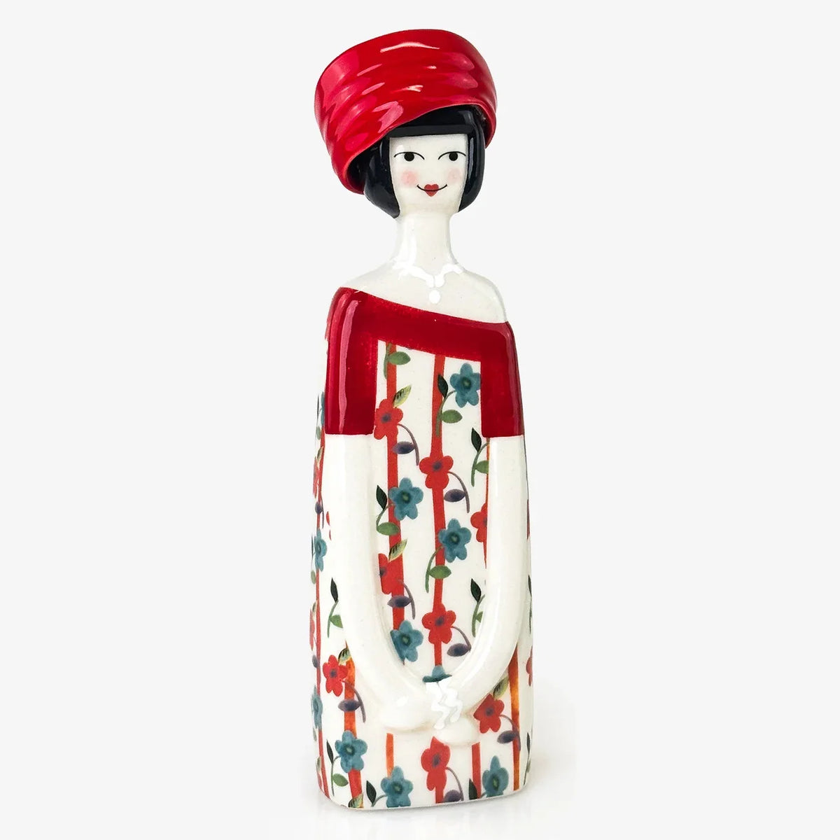 A decorative ceramic figurine of a woman with a red headwrap and a red-and-white floral dress, shown against a plain light gray background.