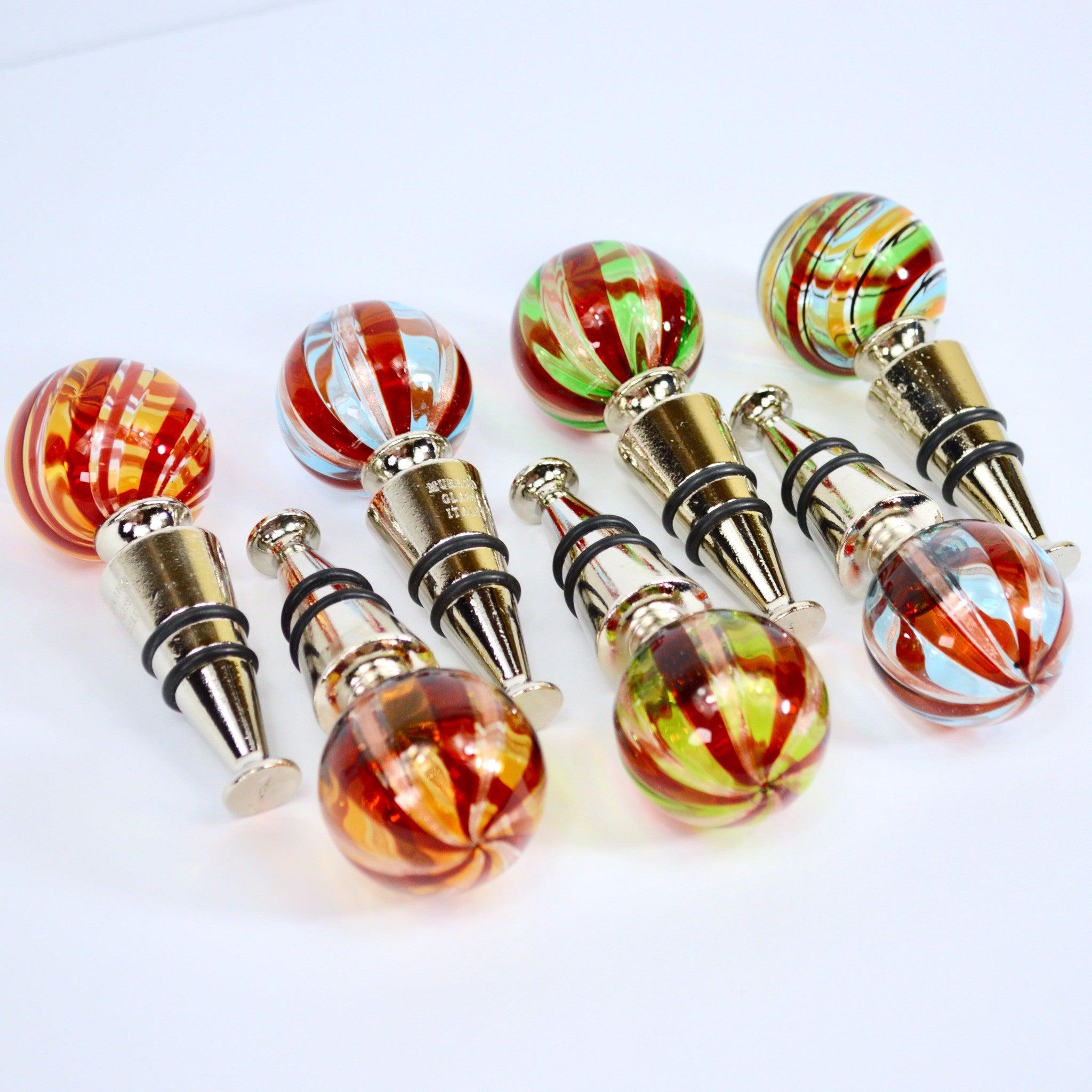 Assorted red Murano glass wine stoppers made in Italy, decorative bottle savers with colorful glass designs.