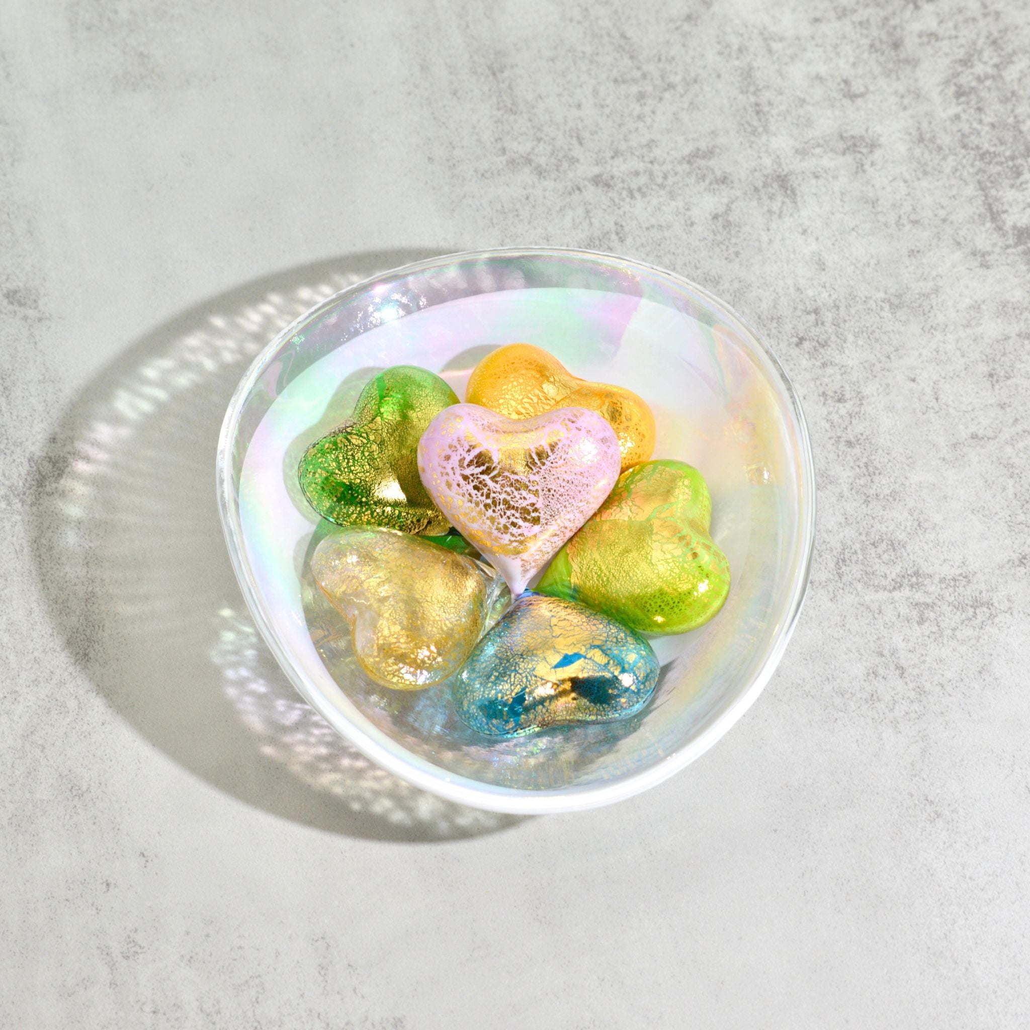Set of three small Murano glass heart figurines in various colors, made in Italy, displayed in a decorative bowl.