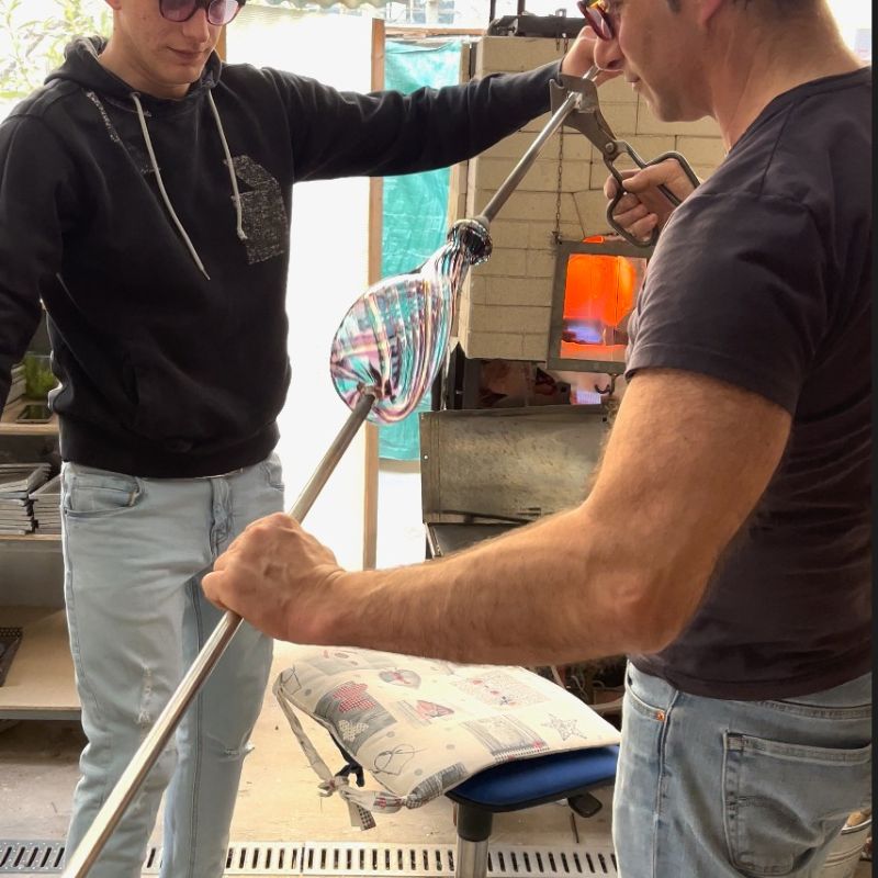 two men glassblowing at furnace in murano, italy