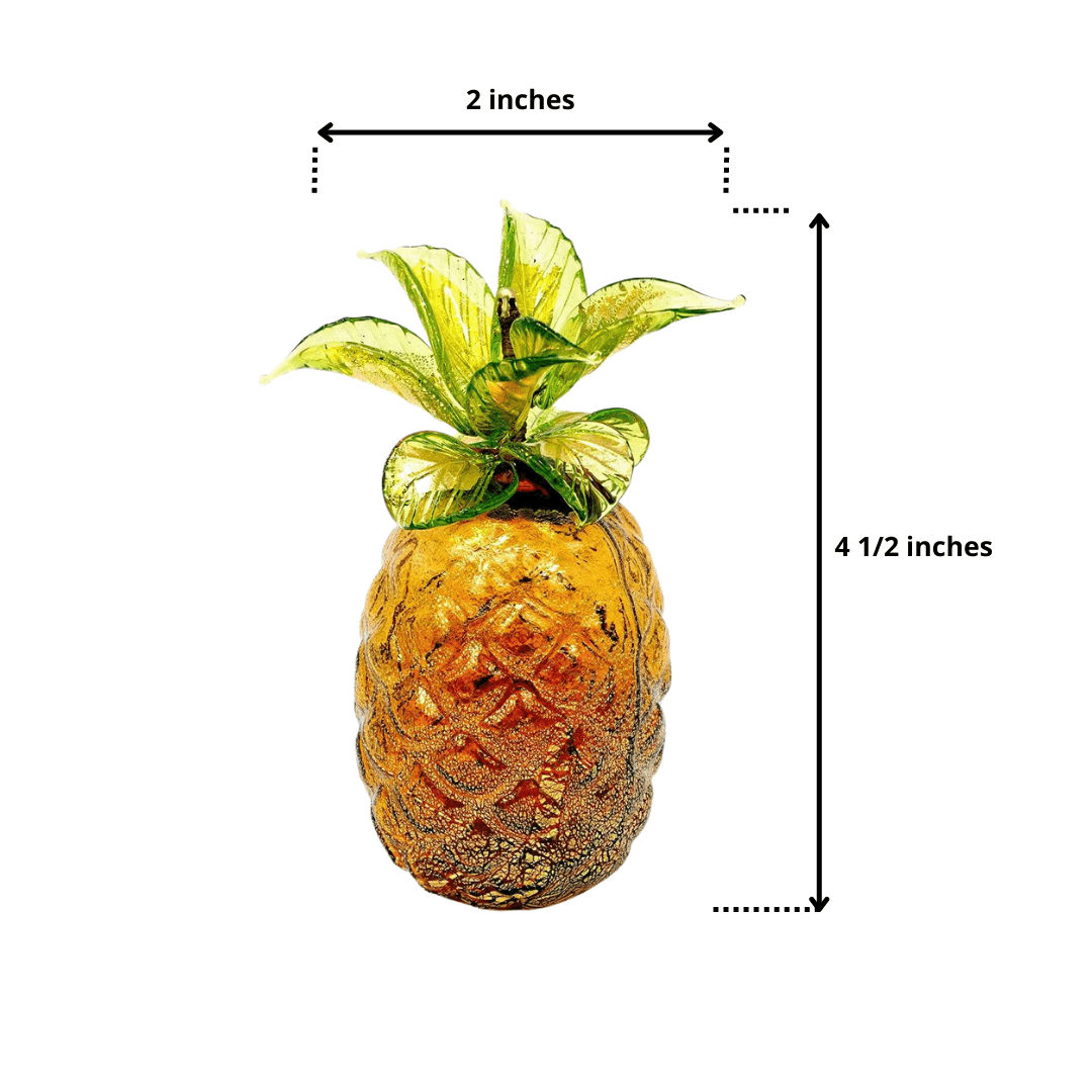 An amber colored Murano glass pineapple with green leaves and ruler marks shows the height and width of this piece.