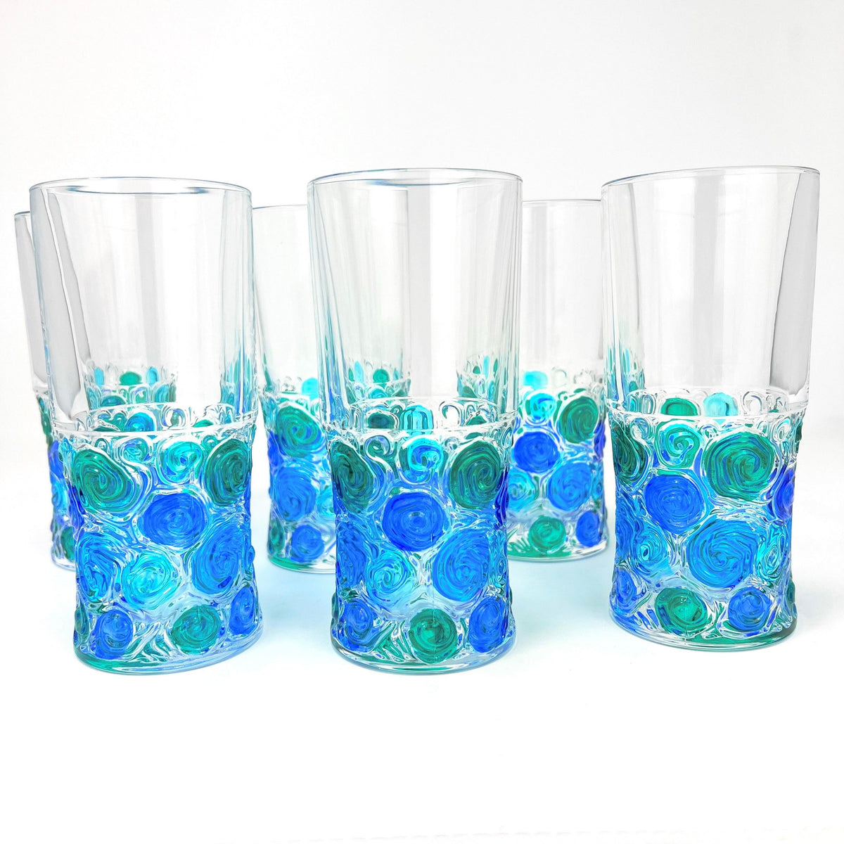 Side view of six Italian Crystal tall drinking glasses with bright blue, green, and turquoise swirls of color on the bottom half.