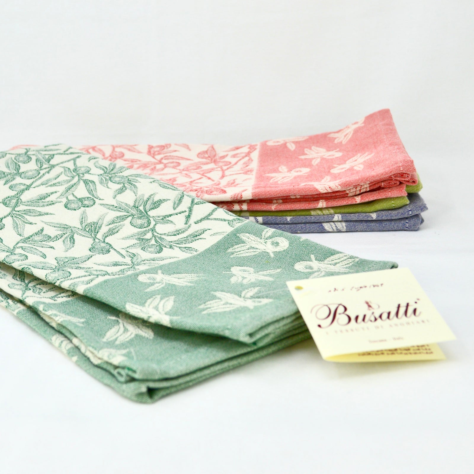 Busatti Oliva kitchen towels in assorted colors, made in Italy, showcasing vibrant, woven table linens with a classic design.
