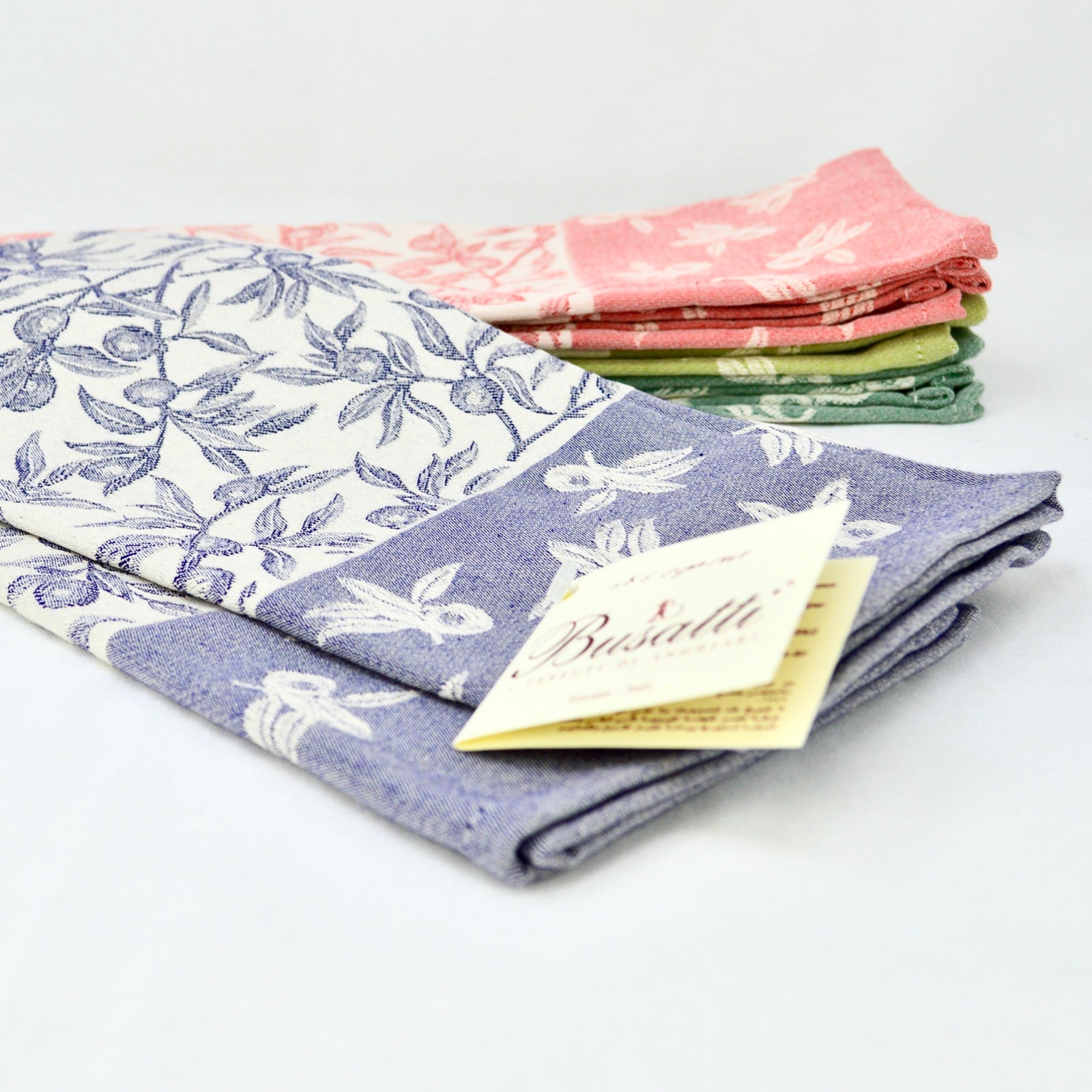 Busatti Oliva kitchen towels in assorted colors, made in Italy, showcasing vibrant, woven table linens with a classic design.