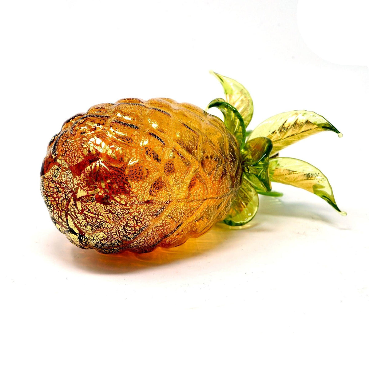 An amber colored Murano glass pineapple lays on it&#39;s side.